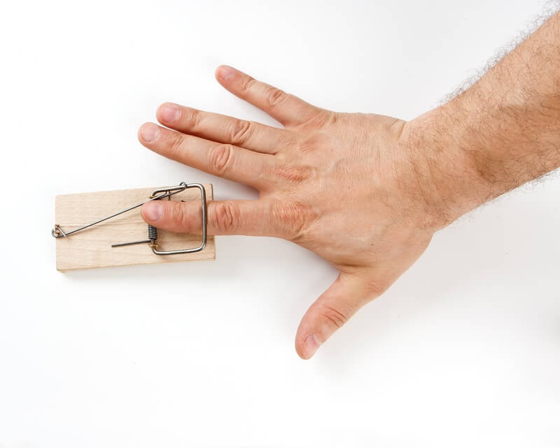 A man's finger getting caught in a mouse trap and getting injured